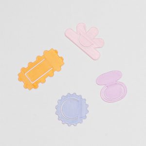 Four page makers in different shapes and colours. One is rectangular with bubbled edges in translucent orange, the second is sun shaped in a translucent light blue colour. The third is formed of two oval shapes atop each other in a translucent lilac, and the third is shaped in a half flower in translucent baby pink.