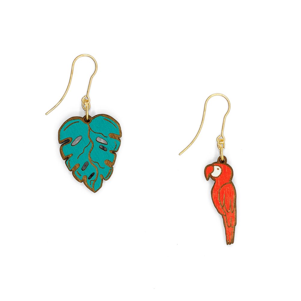 A pair of wood cut drop earrings, one in the shape of a leaf and the other of a red macaw.
