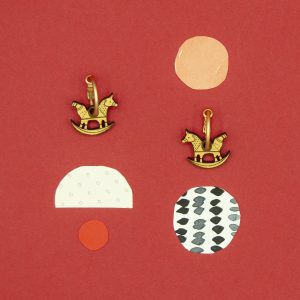 Lasercut wood horse earrings against a red background