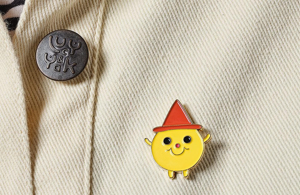 Yellow Guy Enamel pin on cream jacket