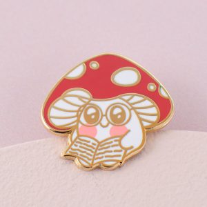 Shroomy Reading Enamel Pin -enamel pin badge of a mushroom reading a book on a pink card background
