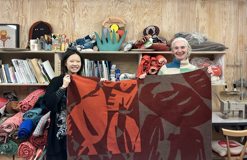 Doudou Huang and Donna Wilson holding red version of Breadworld blanket together