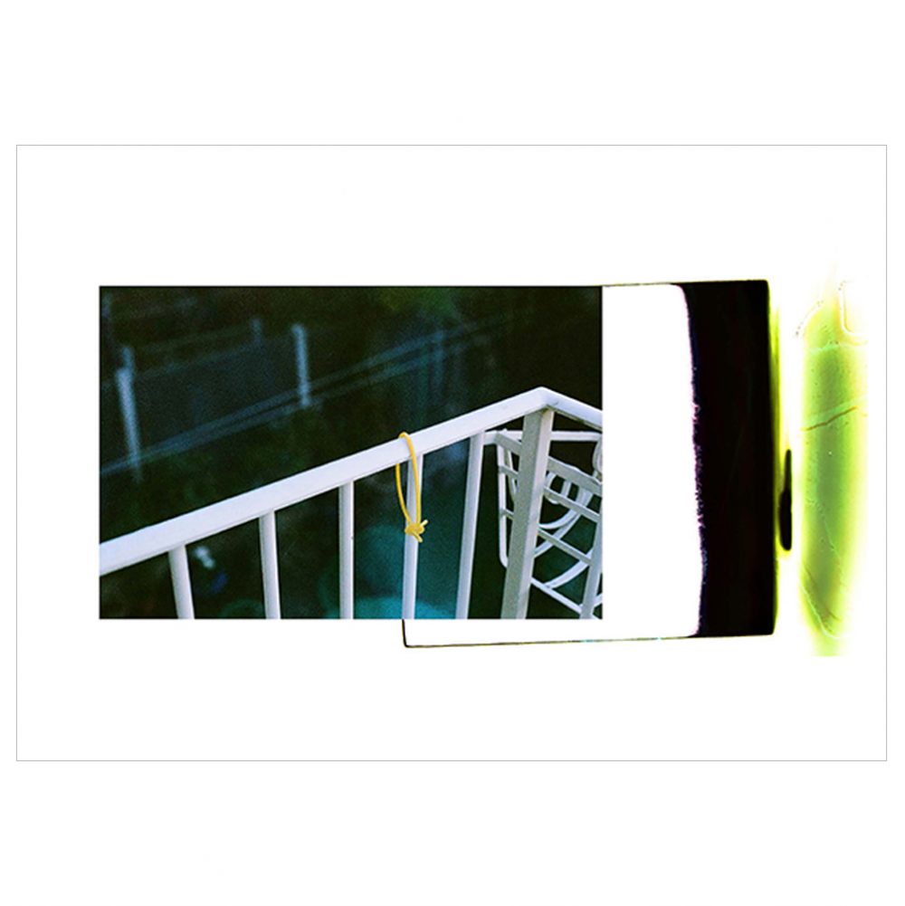 Lost and Found landscape photographs features a set of white railings on the left, with black, white and green block colours on the left. The image is encased in a white border.