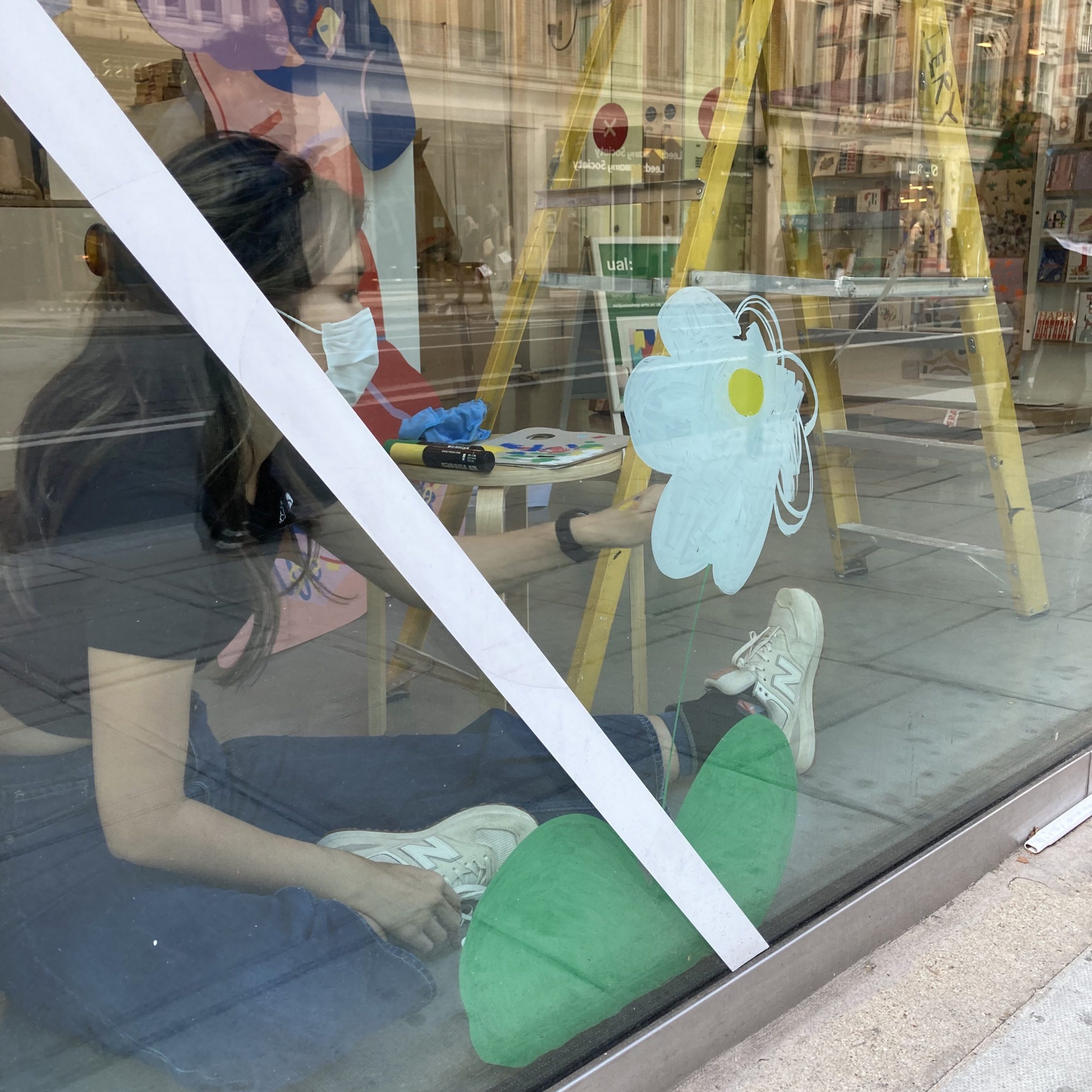 Artist Lily Kong uses a paint pen to create her design on not just a shop's window