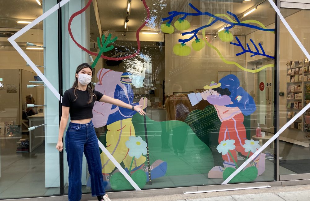 Artist Lily Kong poses in front of her finished design on not just a shop's window