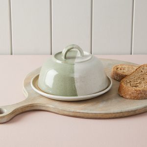 Ceramic butter cloche on a cutting board with bread slices