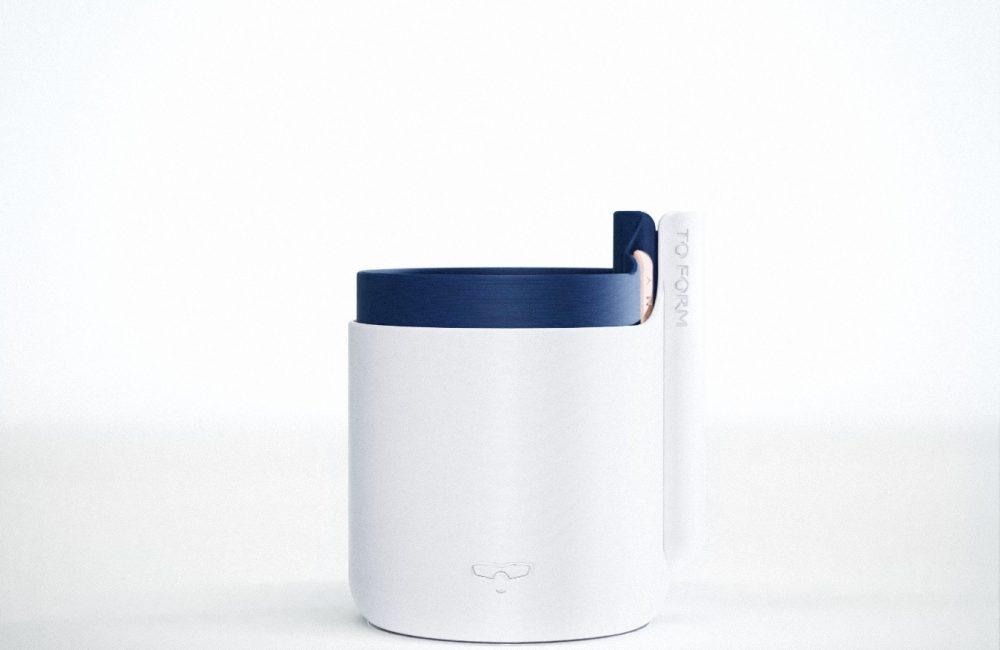 A 3D printed plastic self watering plant pot. The main body is a marbled grey colours, whilst the insert is a dark navy blue. The pot features a logo of a stylised smiling face with sunglasses.
